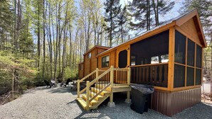 Een chalet met houten gevel, een veranda en een oprit van grind.