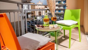 A balcony with a green chair, a small table with a bottle, glasses, and a bowl of snacks. - De Vivo Realty - Stanza Tasso Sorrento (Sorrento)