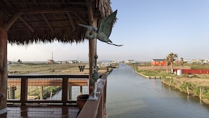 A wooden deck overlooking a calm river with a thatched roof structure.