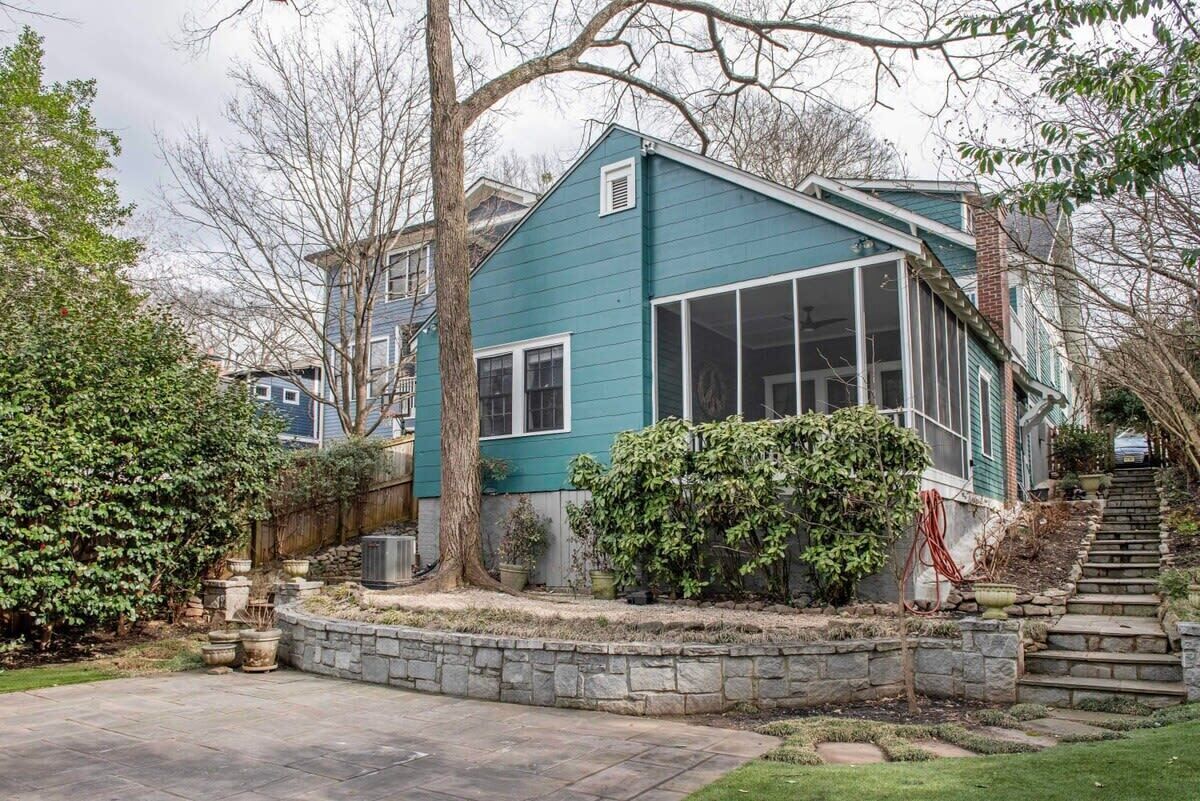 A two-story house with a large bay window, a stone retaining wall, and a stone staircase leading to the front door.