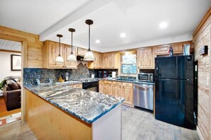 A modern kitchen with wooden cabinets, a granite countertop, stainless steel appliances, and pendant lighting. - Cozy mountain escape in Empire (Empire)