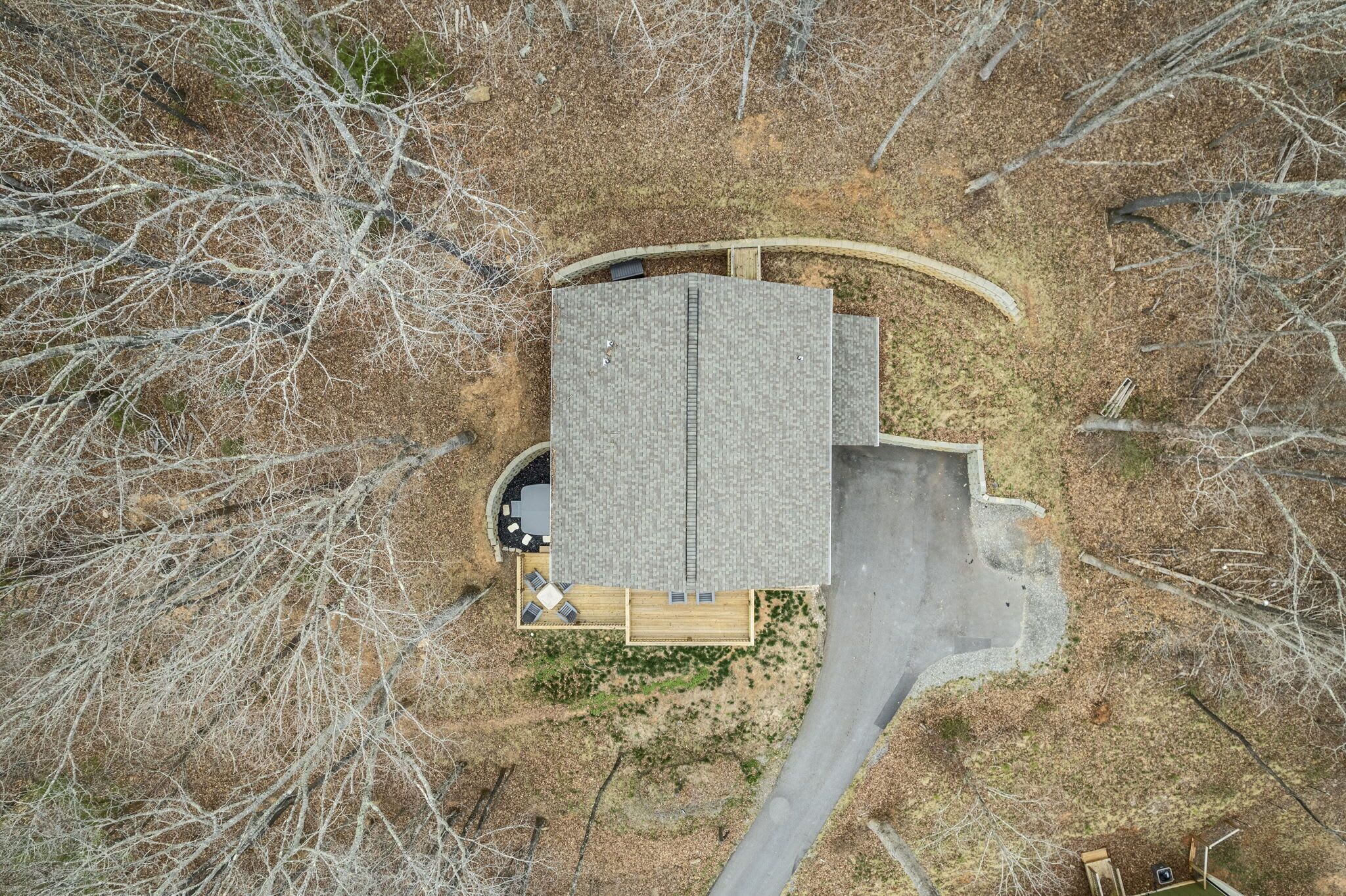 Vue aérienne d’une maison avec un toit en pente, un porche couvert et une allée pavée.