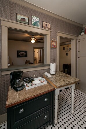 Bathroom features a vanity with a cabinet and mirror, surrounded by patterned wallpaper and framed pictures.