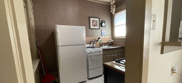 Features a refrigerator, stove, and sink, with framed pictures and a clock on the walls.