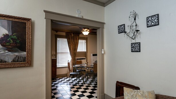 A hallway with a checkered floor leading to a dining area with a table and chairs. - Upper 2 Bedroom Loft Apartment (Memphis)
