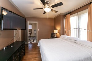 Relax in a stylish room with a large bed, flat-screen TV, and ceiling fan.