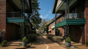 A narrow street lined with brick buildings, each with a balcony and a green awning. - Upper 2 Bedroom Loft Apartment (Memphis)