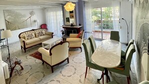 A spacious living room with a large sofa, a dining table with chairs, and a chandelier. - Apartment 120m2 between sea and mountains in Glyfada, Athens Riviera (Glifada)