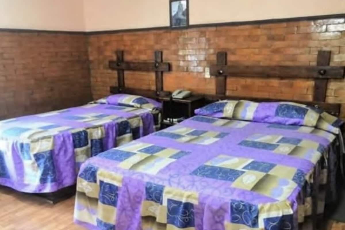 A room with two beds, each with a purple and blue quilted bedspread.