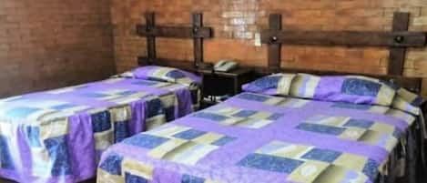 A room with two beds, each with a purple and blue quilted bedspread.