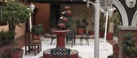 An outdoor patio with a round table, chairs, potted plants, and decorative lanterns.