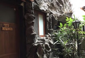 Un edificio de piedra rústico con una puerta de madera que dice "119 ATLIXO".
