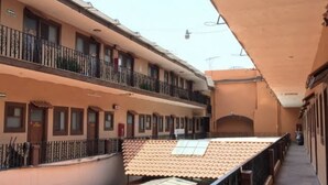A multi-story building with balconies, a tiled roof, and a clear sky. - Hotel San Agustin (Puebla)