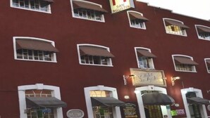 A red building with multiple windows and awnings, a sign reading "San Agustin," and a sign for "Honda." - Hotel San Agustin (Puebla)