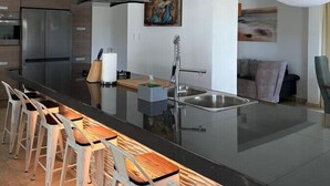 A modern kitchen with a large island, stainless steel appliances, and bar stools.