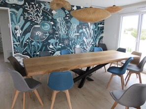 Ein moderner Konferenzraum mit einem großen Holztisch, blauen und grauen Stühlen und einer lebendigen Wand im Unterwasser-Design.