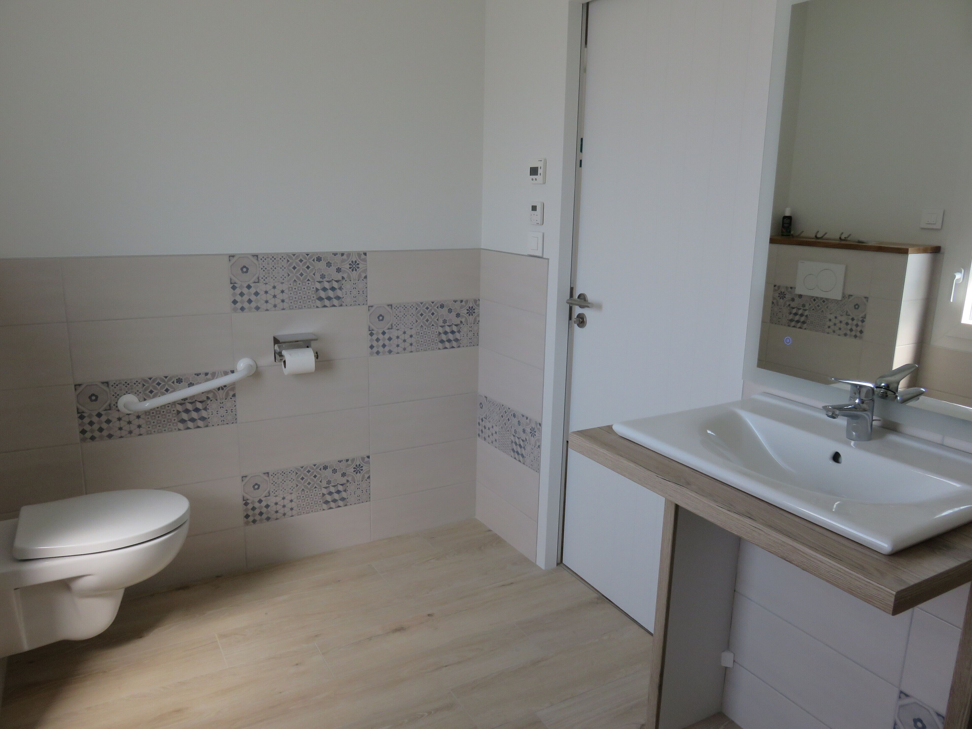 A bathroom with a toilet, a sink, and a mirror.