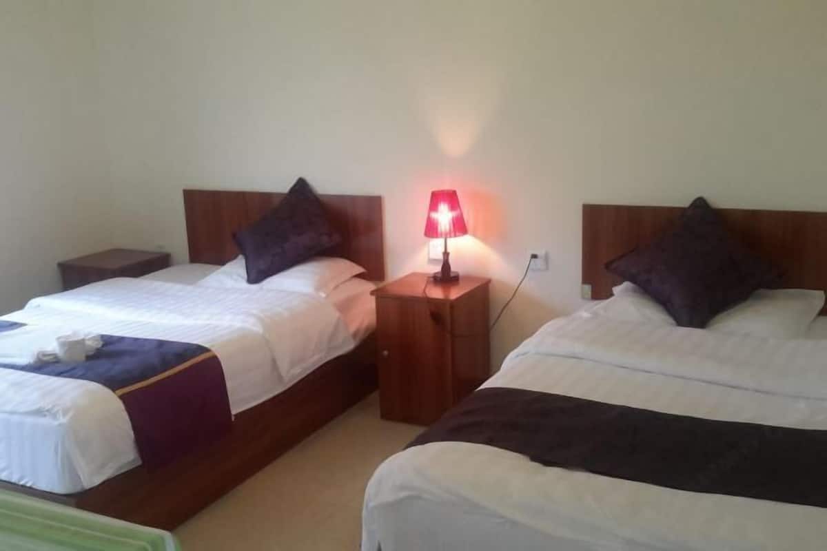 Two single beds with wooden headboards, a nightstand with a red lamp, and a small table between the beds.