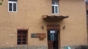 A building with two windows, a stone foundation, and a wooden door with signage.