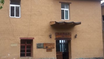 A brick building with a signboard, a door, and a window.