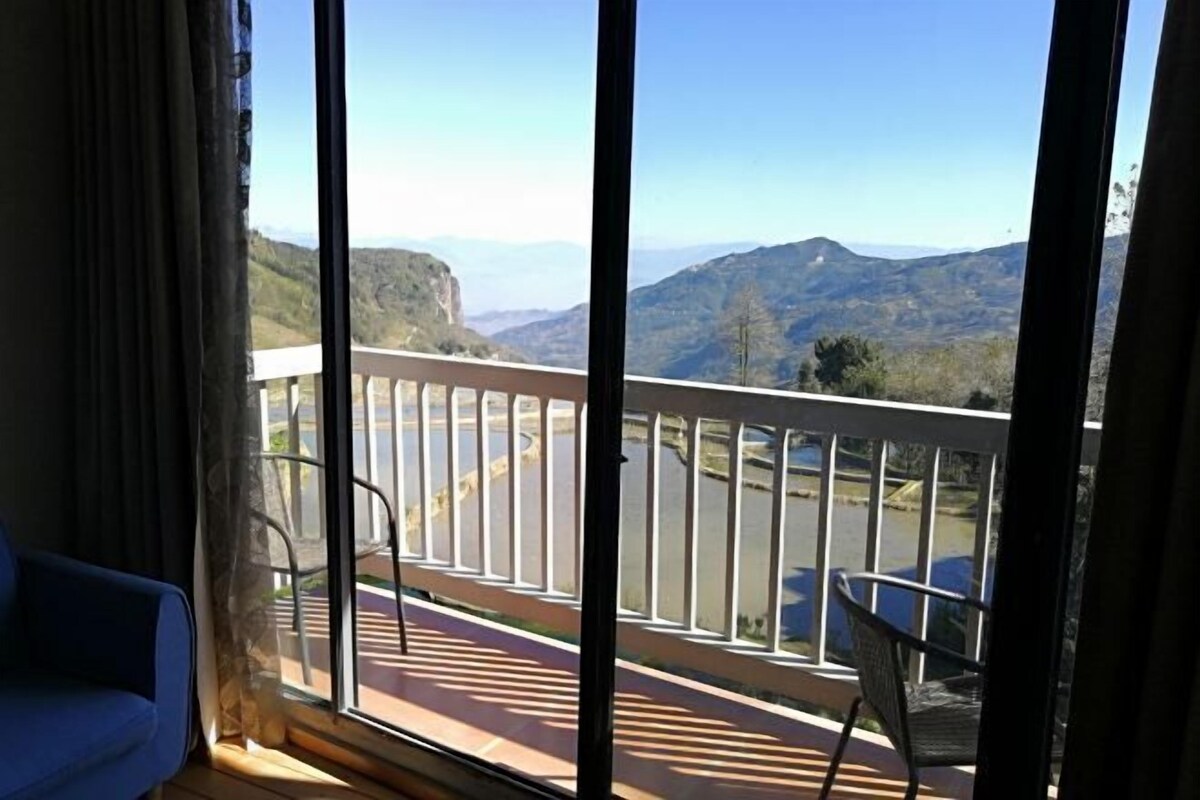A balcony with a view of mountains and a road.