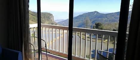 A balcony with a view of mountains and a road.
