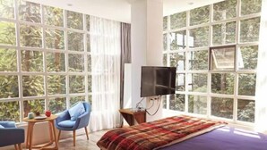 A bedroom with a large bed, a TV, a small table, and a chair. - Jacky's Guesthouse (Yuanyang)
