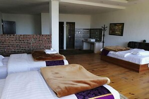 Habitación de hotel con dos camas, una pared de ladrillo, un baño y un cuadro en la pared.