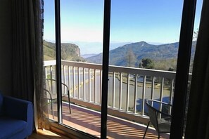 Un balcón con vistas a las montañas, una silla y una mesa.