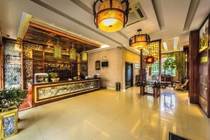 A hotel lobby with a reception desk, hanging lanterns, and potted plants. - Jiangpao Express Inn (Wuyishan)