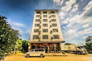 A multi-story building with a flat facade, air conditioning units, and a commercial entrance with signage. - Jiangpao Express Inn (Wuyishan)