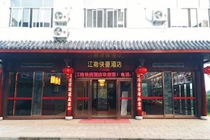 Un bĂątiment traditionnel chinois, avec un toit recouvert de tuiles, des lanternes rouges et une enseigne indiquant quâil sâagit dâun hĂŽtel.