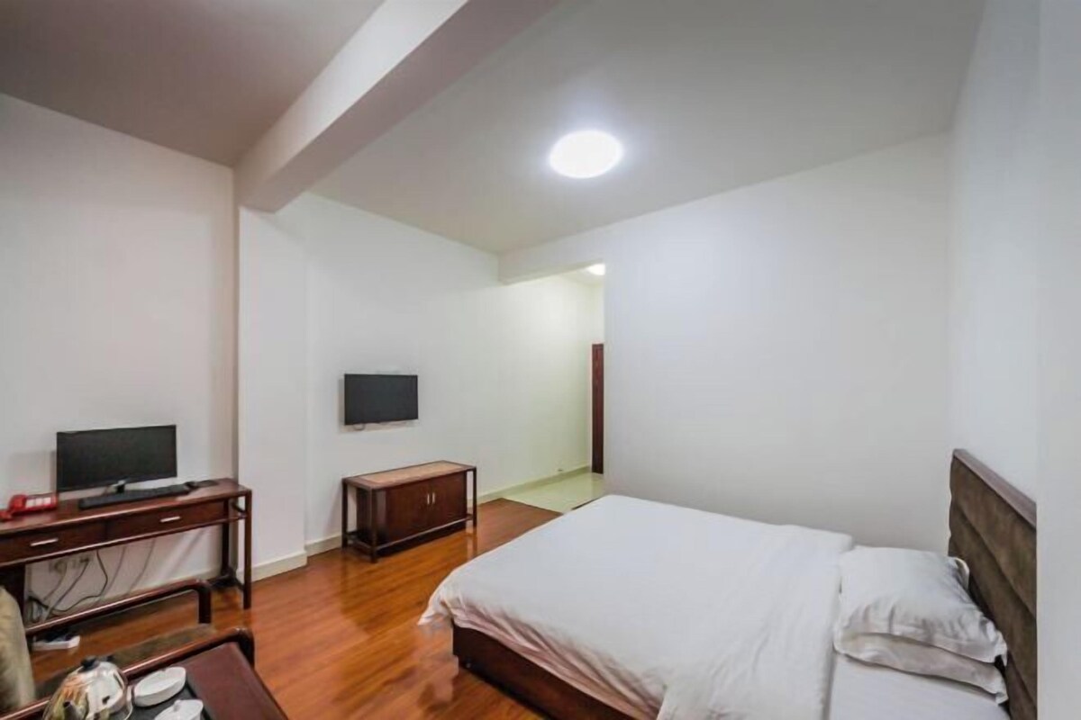 A bedroom with a bed, a desk, a television, and a wardrobe.