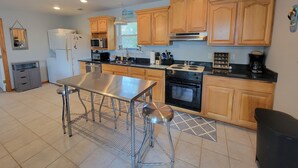 A modern kitchen with wooden cabinets, stainless steel appliances, and a central island. - Tybee Pink House (Military & Veteran Discount) (Tybee Island)