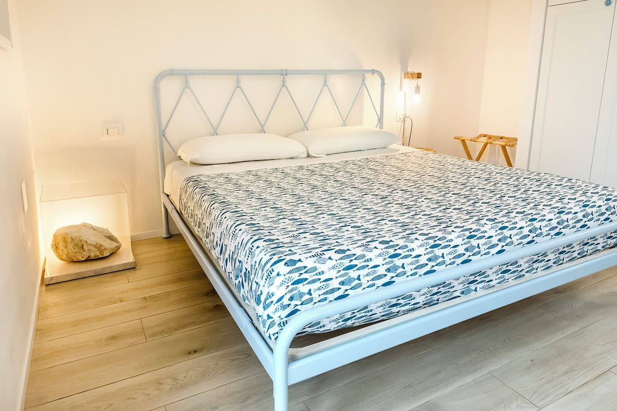 A bed with a white metal frame, a patterned bedspread, and two pillows.