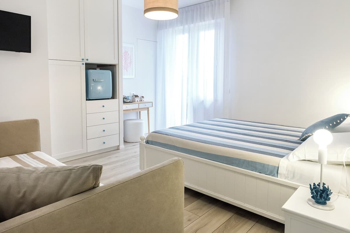 Un dormitorio moderno con cama, mesita de noche, lámpara y un escritorio con silla.