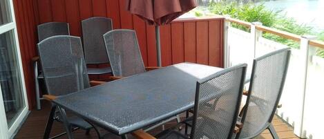 Un espace extérieur abrité, avec une table et des chaises, donnant sur un port de plaisance.