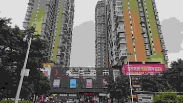 A high-rise building with multiple balconies and a commercial area below.