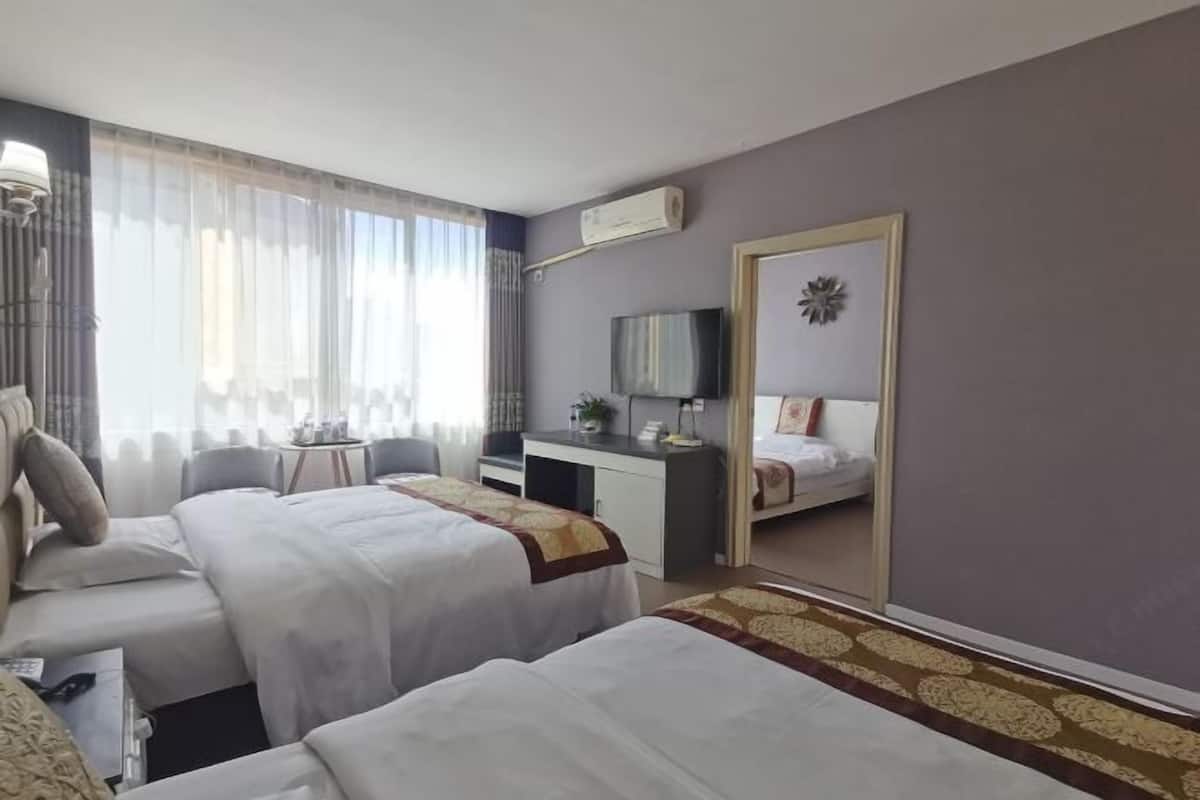 Hotellihuone, jossa on kaksi sänkyä, työpöytä, tuoli, televisio ja suuri peili.