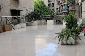 Une cour spacieuse agrĂ©mentĂ©e de plantes en pot, dotĂ©e dâune rambarde en mĂ©tal et dâun sol en bĂ©ton.
