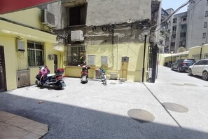 A narrow street with parked motorcycles and a building with a yellow facade.