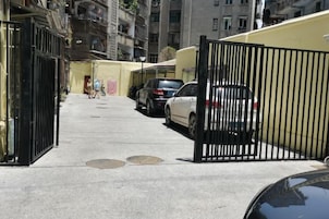 Una calle estrecha con coches aparcados y un acceso con puerta.