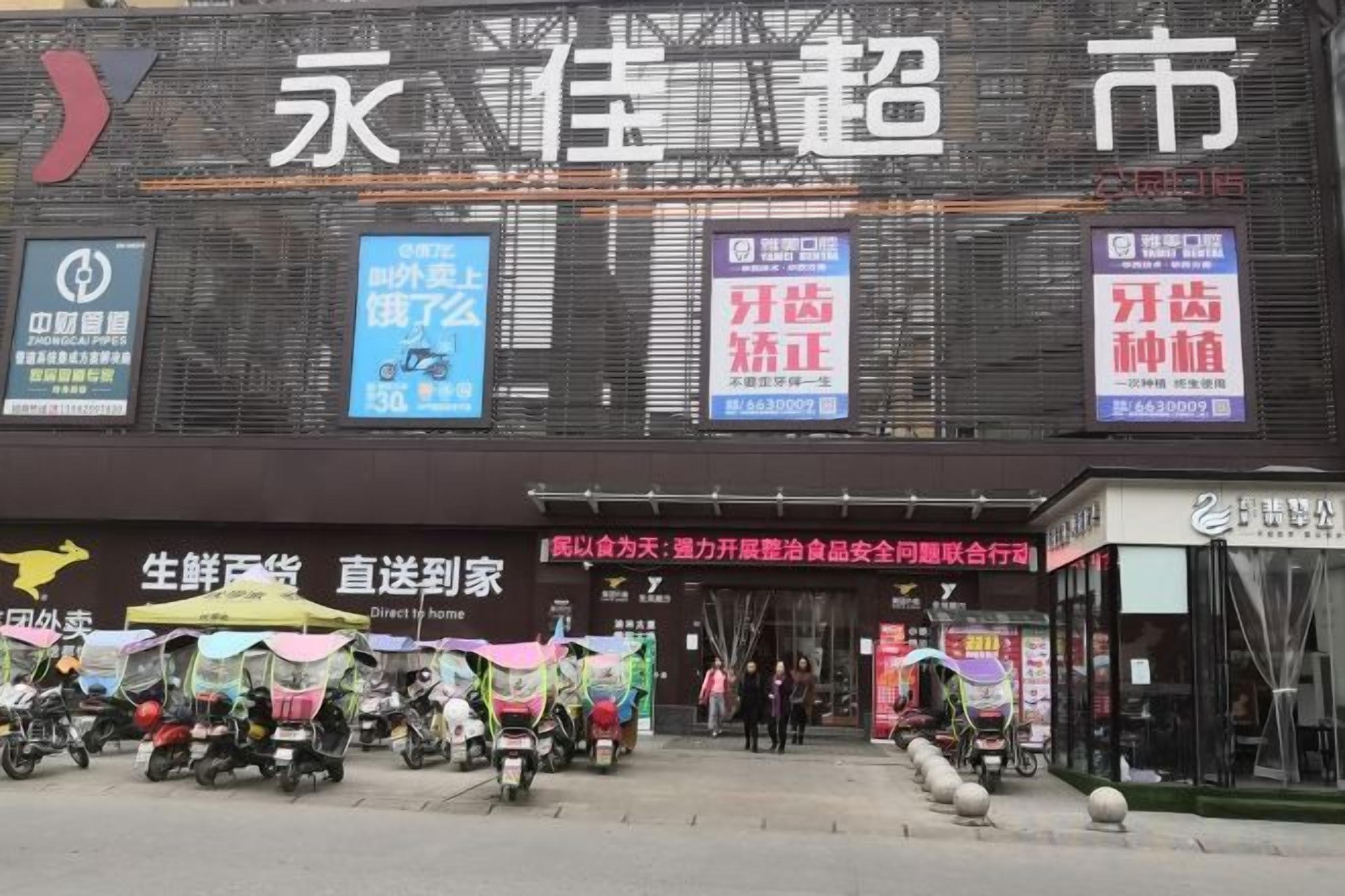 A commercial building with multiple storefronts and a pedestrian area with food stalls.