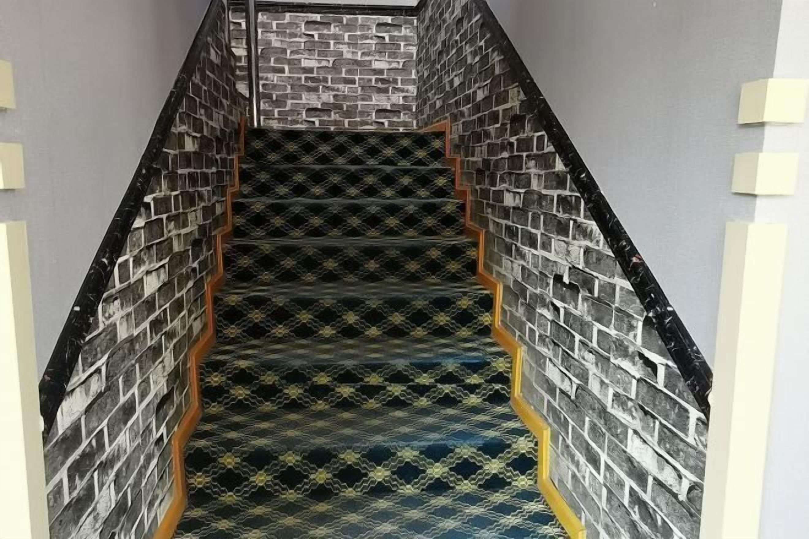 Una escalera con alfombra estampada y diseño de pared de ladrillo.