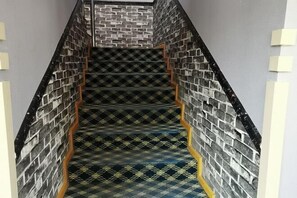 A staircase with a patterned carpet and brick wall design.