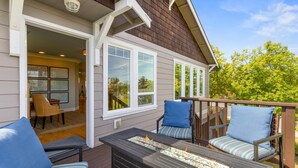 A deck with outdoor furniture, a fire feature, and a view of the interior. - Salish Coast Retreat a High End Home with Views (Port Angeles)