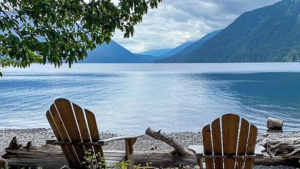 Two Adirondack chairs facing a calm lake with mountains in the background. - Salish Coast Retreat a High End Home with Views (Port Angeles)