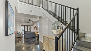 Un intérieur moderne comprenant un escalier, un espace de vie avec un canapé et une table basse, ainsi qu’un meuble décoratif.