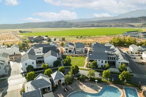 Un quartiere residenziale con case moderne, una piscina e vista su campi verdi e montagne.