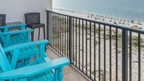 A balcony with turquoise chairs, a wooden deck, and a view of the beach and ocean. - Island Winds West by Brett/Robinson Vacations (Gulf Shores)